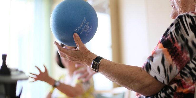 Eine Seniorin hält einen kleinen Ball auf der Hand.