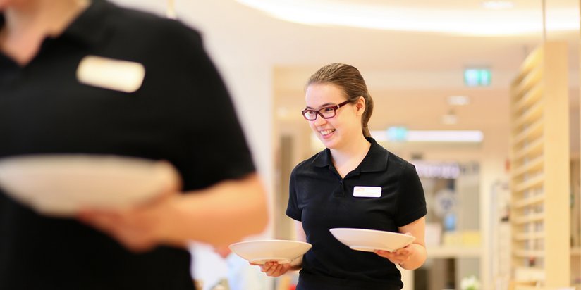 Mitarbeiterinnen servieren das Essen in der Cafeteria.