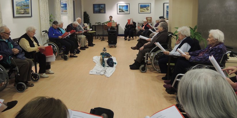 Senioren sitzen im Kreis und singen gemeinsam.