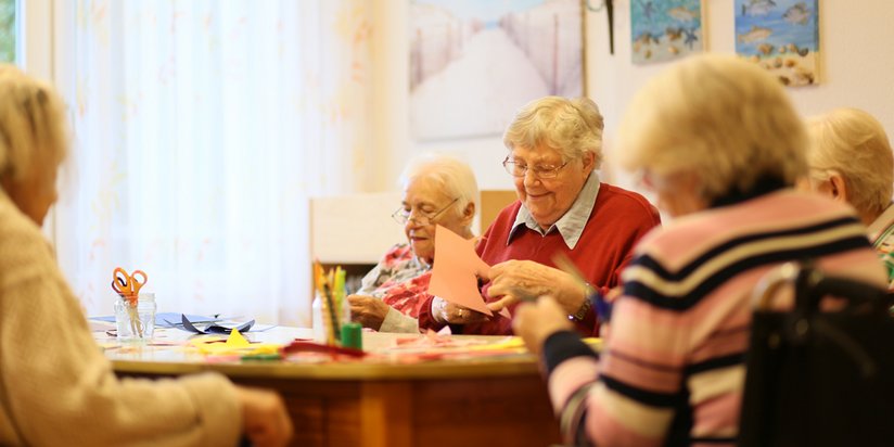 Eine Gruppe Seniorinnen ist mit Bastelarbeiten beschäftigt.